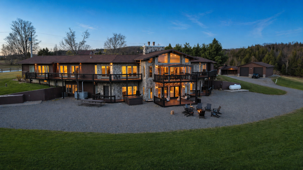 Back of lodge with fire pit, hot tub, decks and outdoor dining table access from lower level bar.