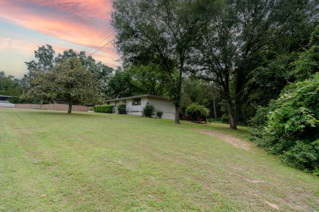 A spacious yard surrounded by mature trees.