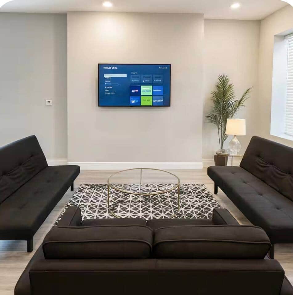 spacious living room featuring a large flat-screen TV and 3 comfortable futon sofa beds, providing plenty of seating during the day and extra sleeping space at night. The open-concept layout connects directly to the kitchen and dining area.