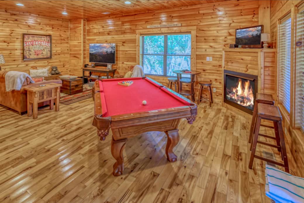 Game room with pool table, game barrel, 43" TV and 65" TV with DishNetwork, and gas fireplace.