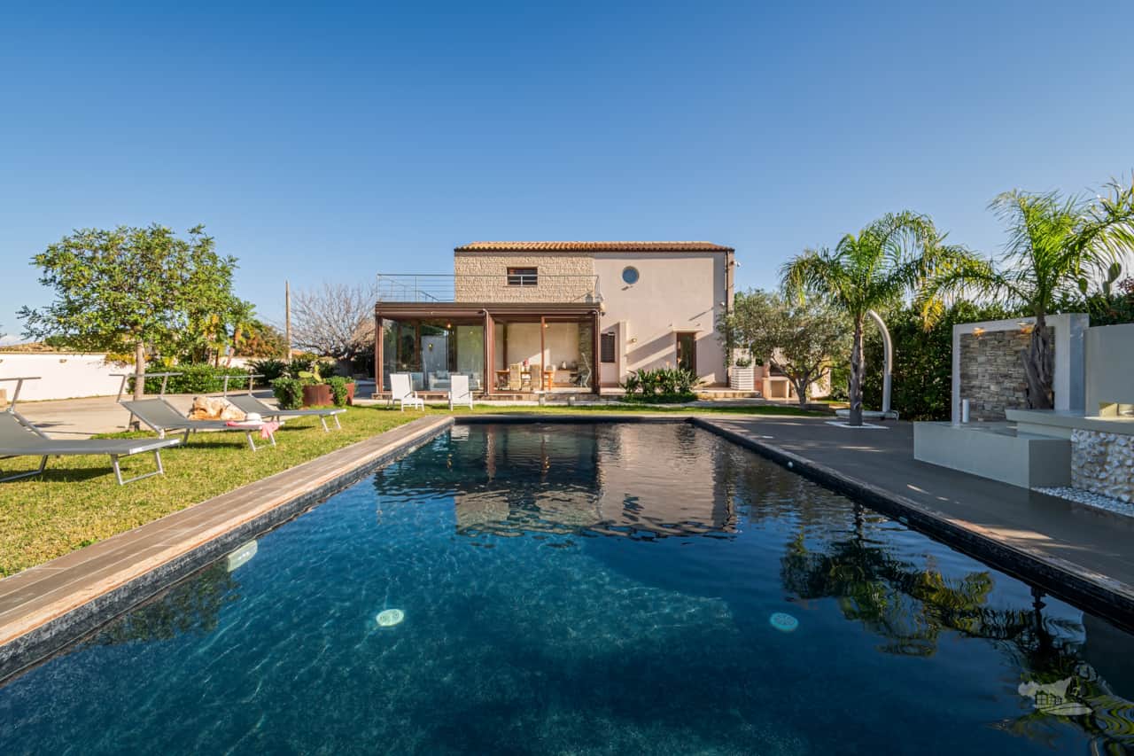 The villa’s enchanting outdoor area, centered on a modern pool surrounded by greenery. 