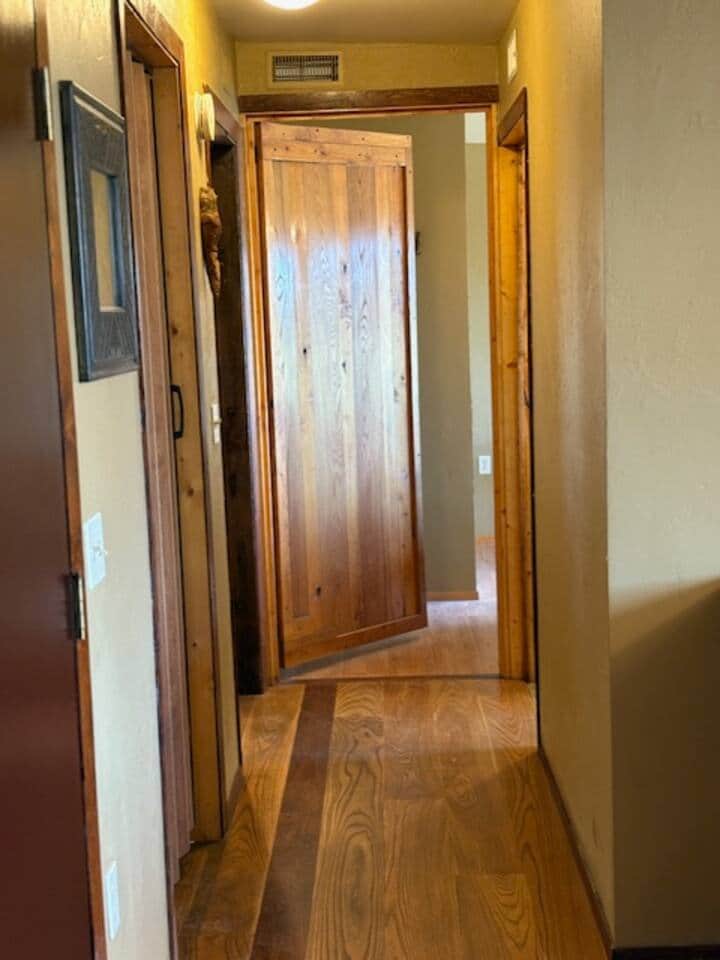 This hallway leads to the two bedrooms and bathroom, showcasing a handcrafted door.