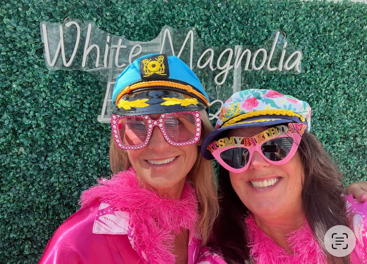 Friends in matching outfits in front of White Magnolia Galveston photo wall
