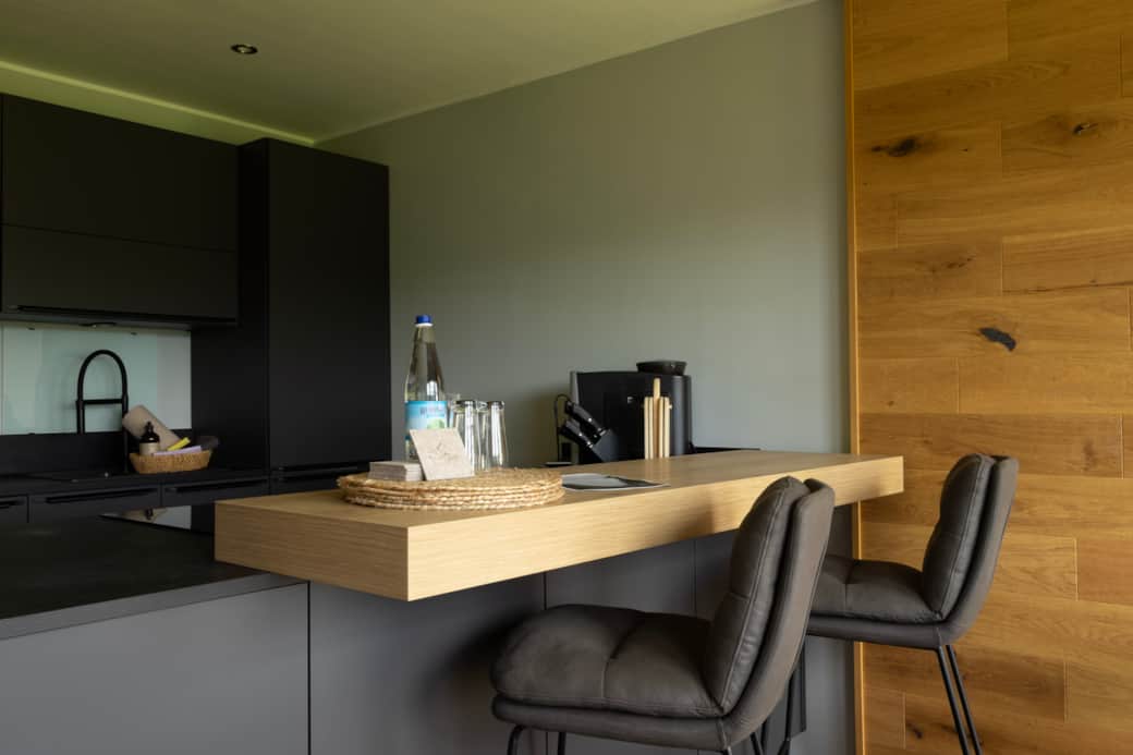 Genussbereich: Küche mit Bar und stilvoller Eichenrückwand im Blick.