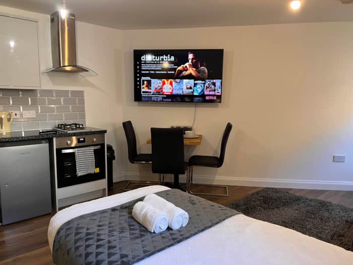 Contemporary room with a kitchen, wall-mounted TV and dining table