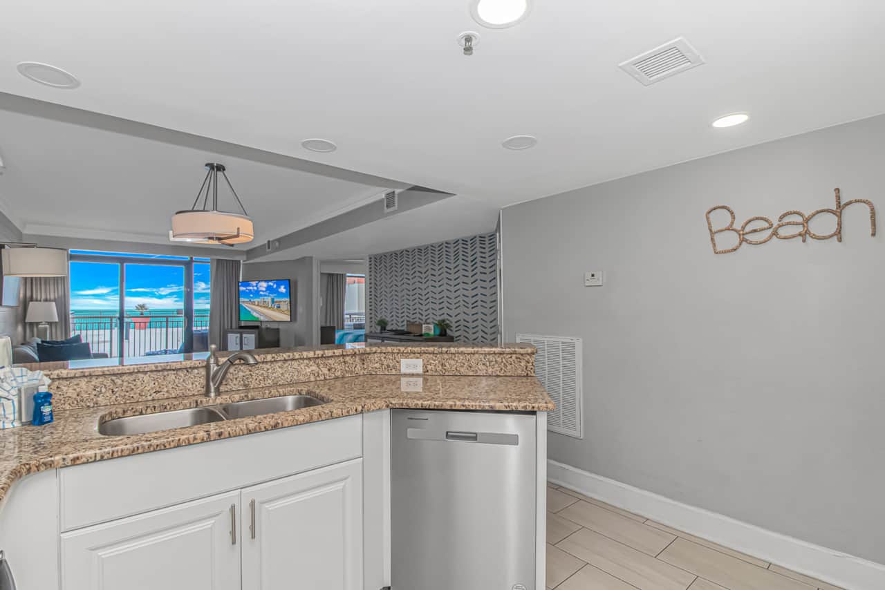 Bright, updated kitchen featuring granite countertops, stainless steel appliances, and an open layout overlooking the living room and ocean.