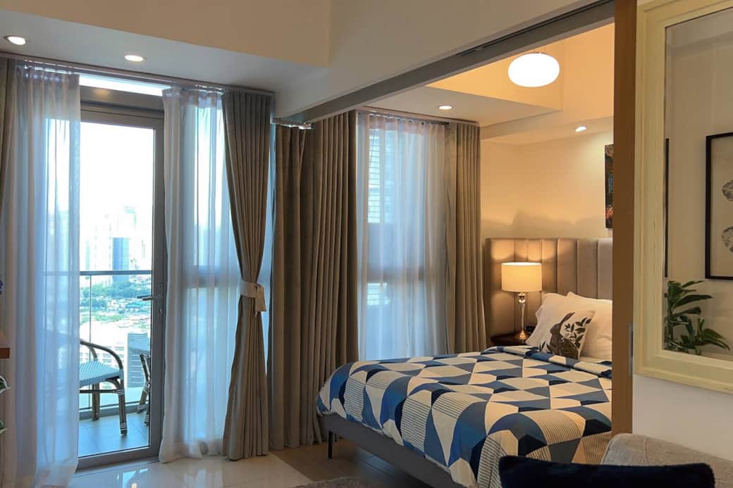 The bedroom is furnished with a queen-size bed and a comfortable mattress, covered with soft bed linens, along with black-out curtains.