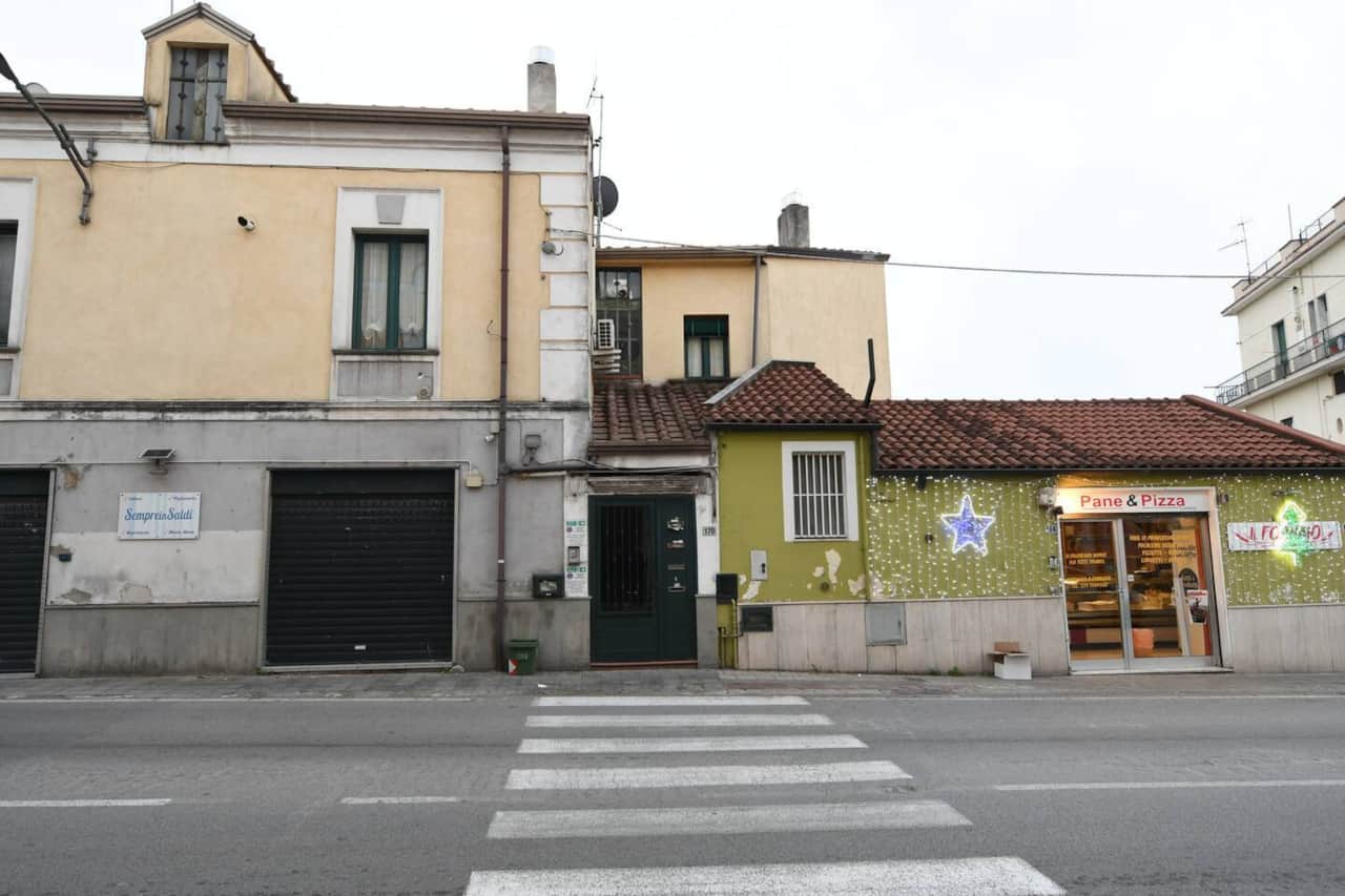 Portone di ingresso di colore verde, sulle strisce pedonali, di fianco al fornaio