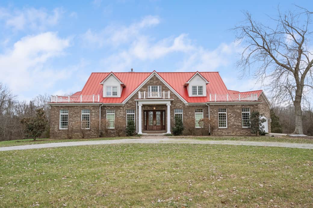 Full exterior view of the spacious brick home with signature red roof and grand front entrance. Full exterior view of the spacious brick home with signature red roof and grand front entrance.