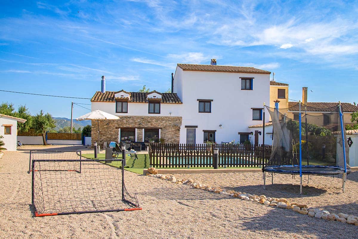 Patio exterior amplio con zona de juegos y camas elásticas | Masía de Cholito
