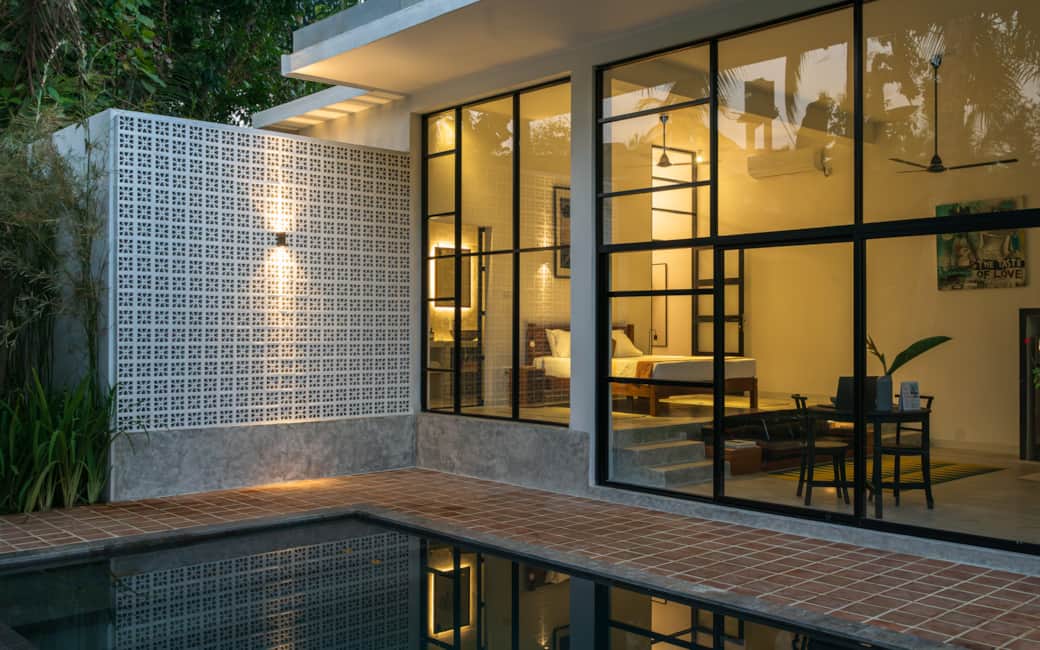 Evening, from outside. The pool, then the house behind.