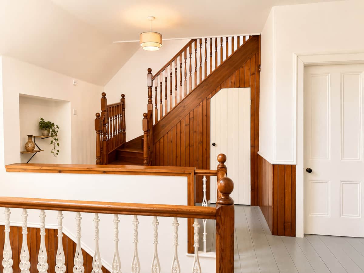 Upstairs landing with Victorian turned banisters and a staircase rising to the loft.
