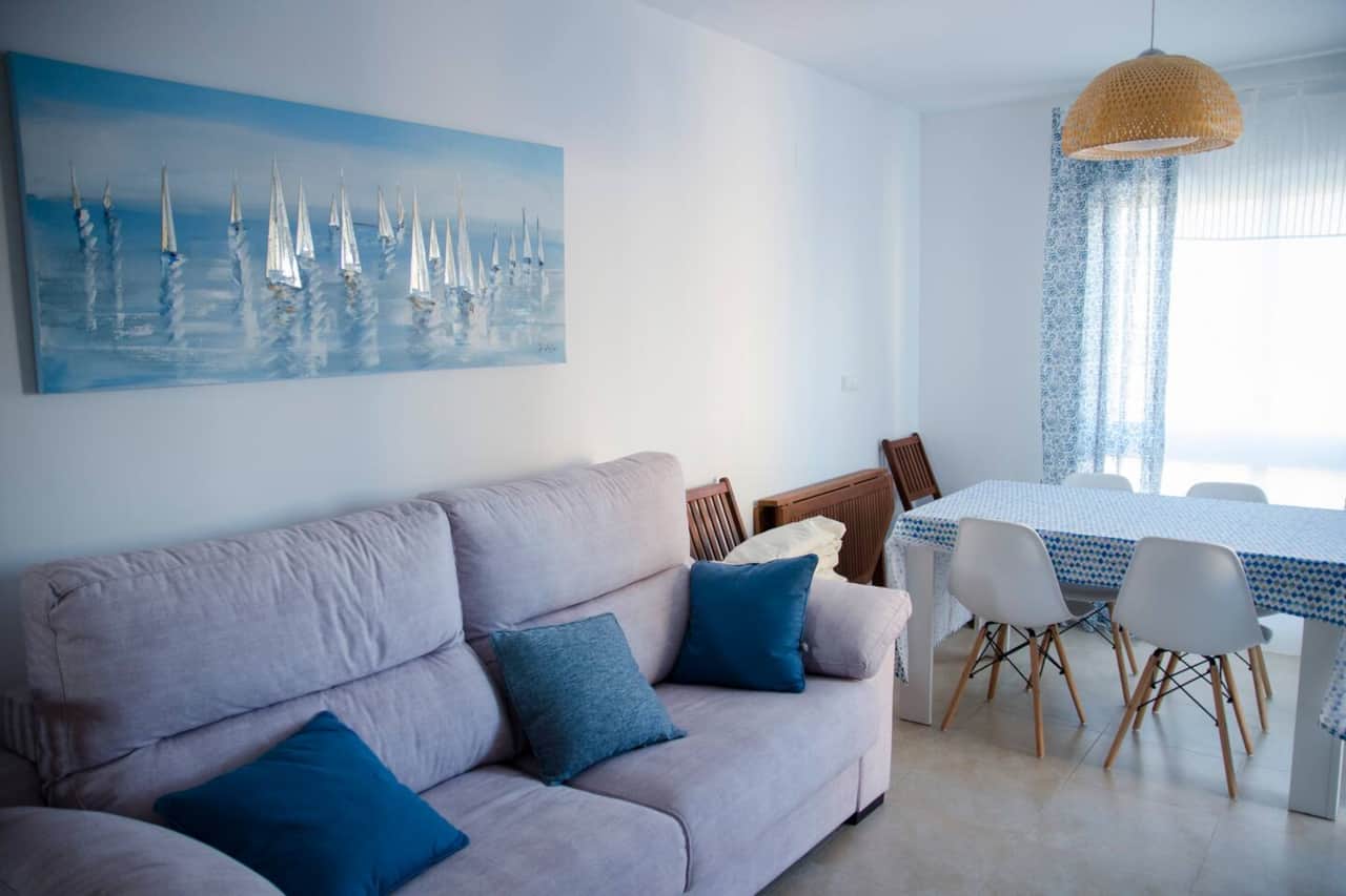 Salón con sofá y comedor junto al ventanal