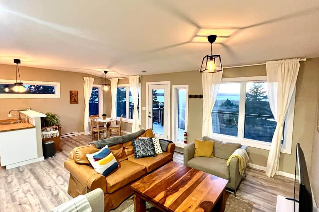 Bright open-plan lounge with coastal views, deck access, and cozy seating Bright open-plan lounge with coastal views, deck access, and cozy seating