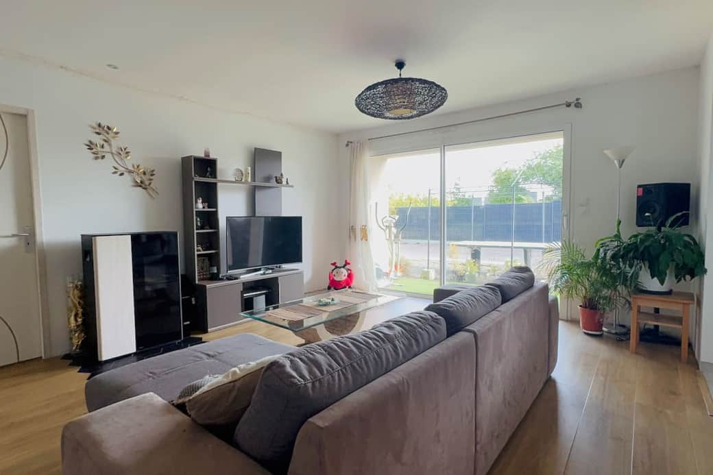 Grand salon avec canapé convertible, TV écran plat et cheminée.