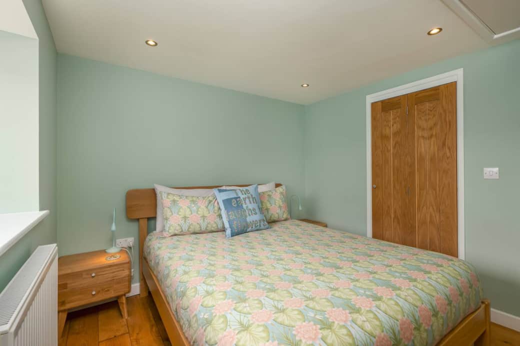 Bedroom showing kingsize bed and bi-fold wooden door leading to the hallway.