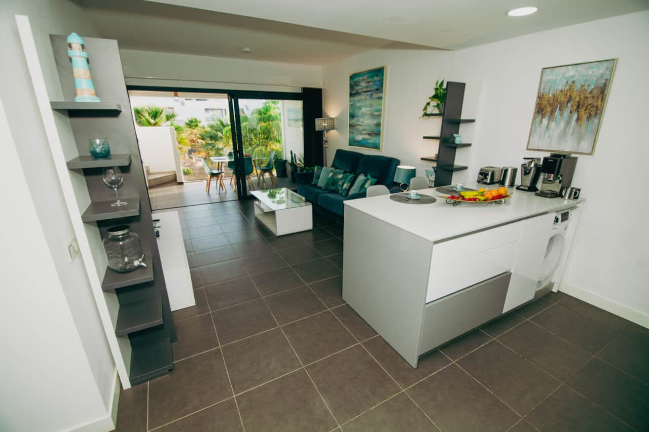Cocina americana con isla central tipo barra de desayuno y vistas a la terraza, ático