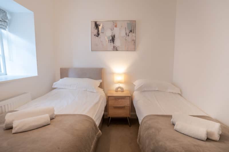 Twin beds with rolled white towels in the Windermere family apartment