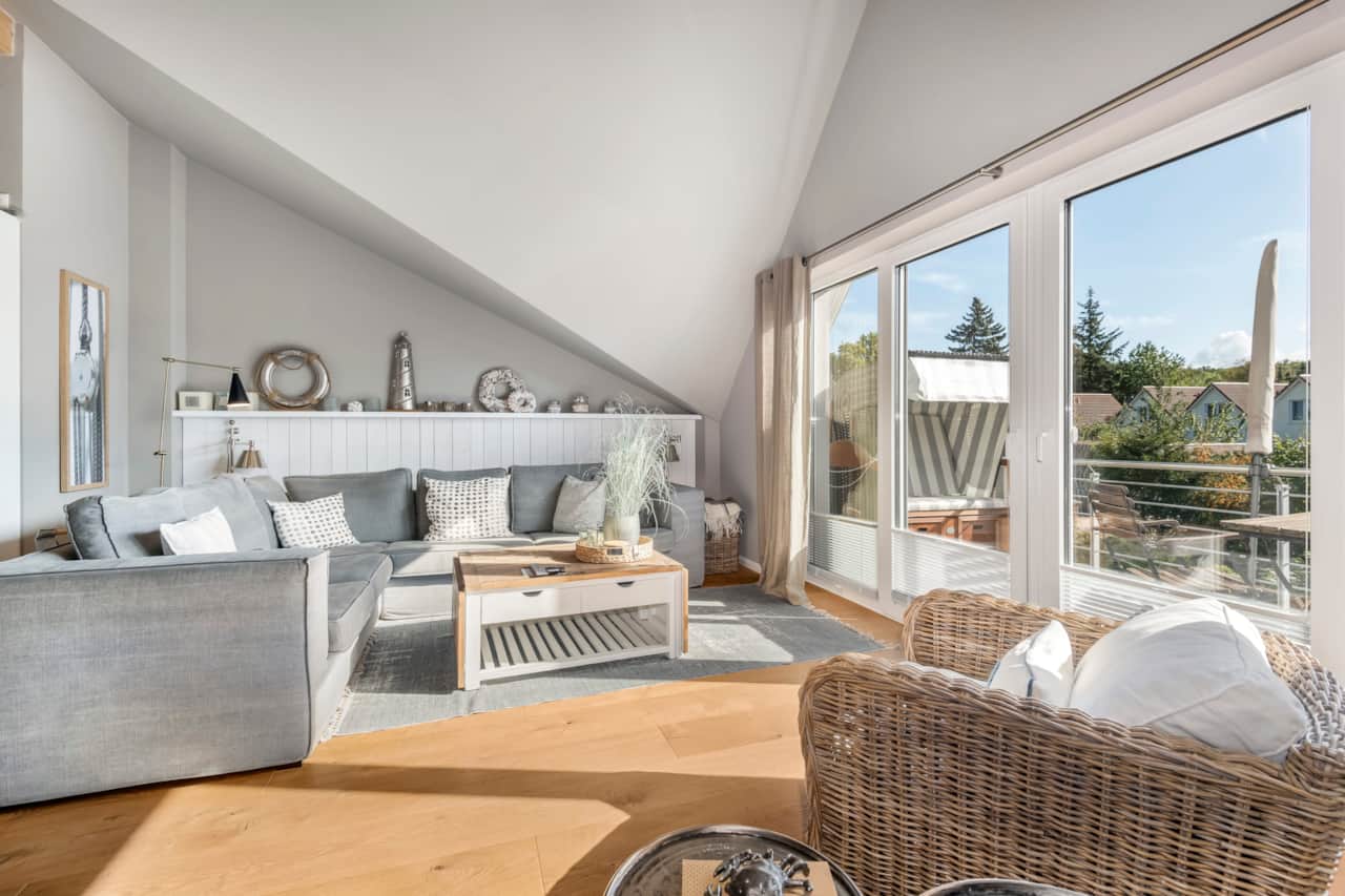 Wohnbereich der Ferienwohnung Seesucht Hohwacht mit großzügiger Fensterfront, Sofa und gemütl