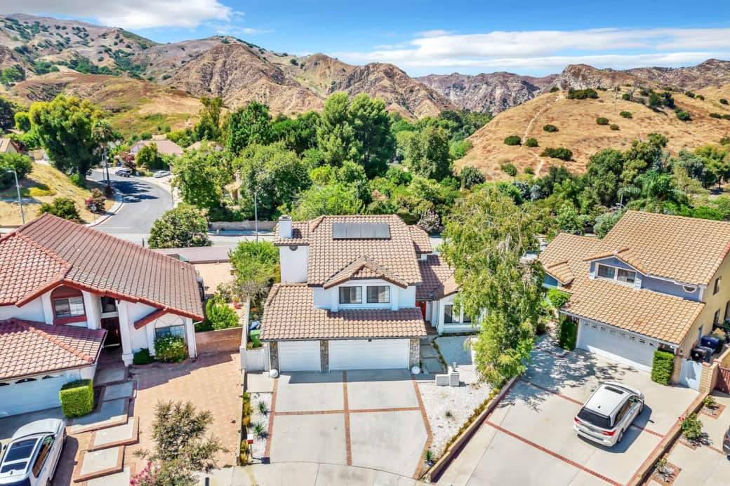 Aerial views highlight the home among mature trees and hills for a stunning hillside location.