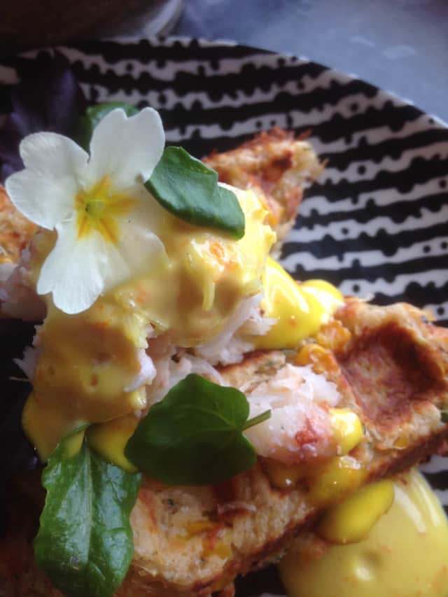 A plated waffle dish with sauce and a flower garnish at Ninth Wave