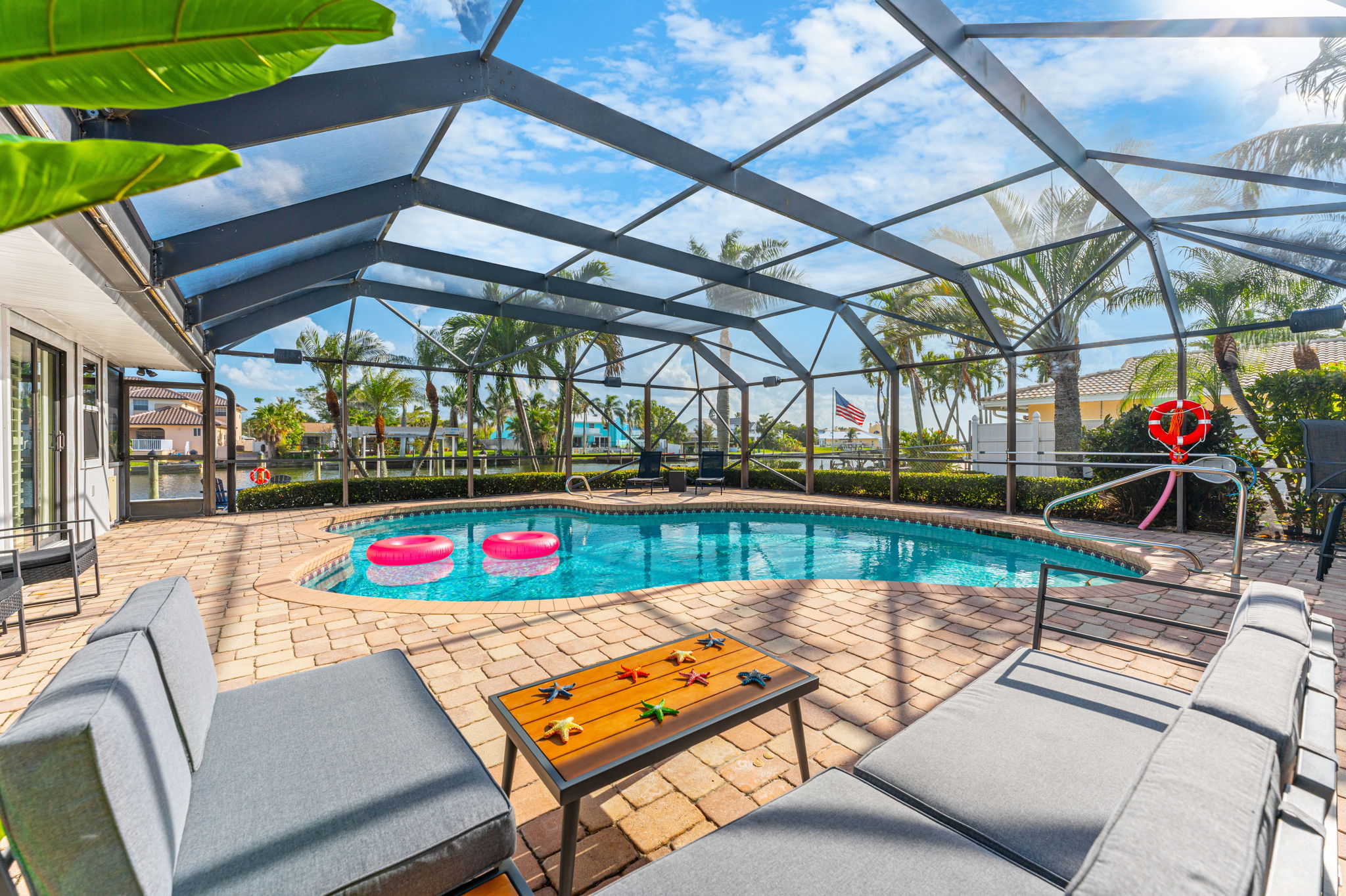 Enjoy a screened pool with lounge chairs, pink floats, and tropical vibes, just minutes from the bea