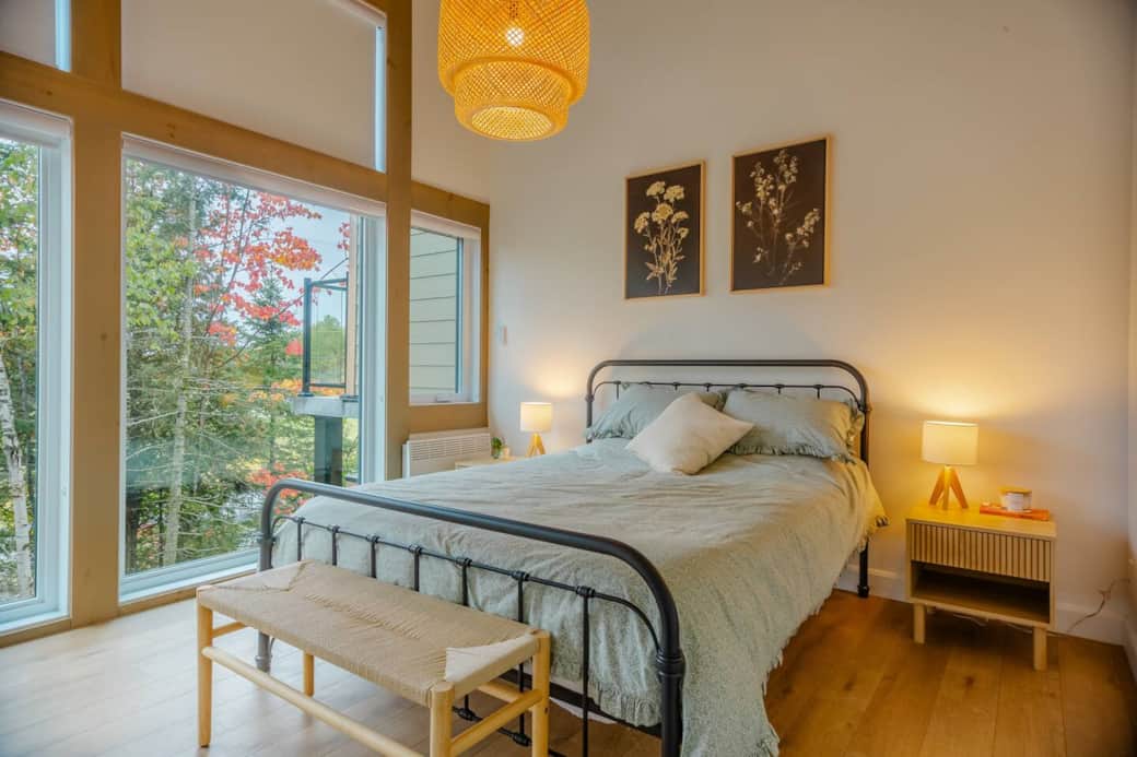 Chambre principale avec vaste mur de fenêtres offrant une vue directe sur le parcours de golf.