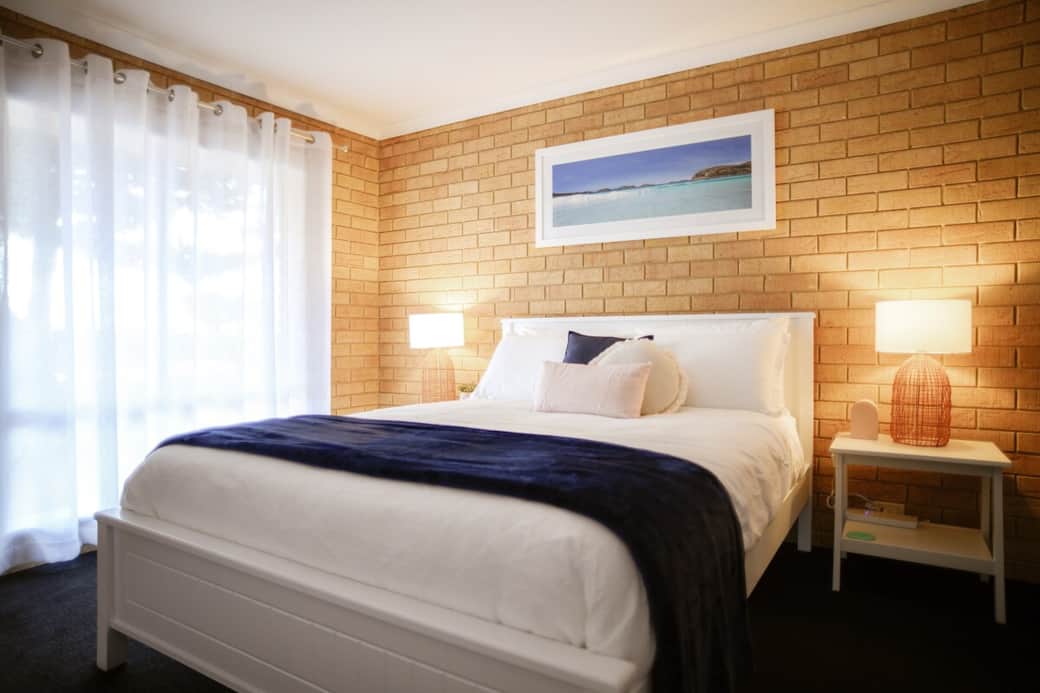 Main bedroom has a queen bed with quality linen, a double wardrobe with hangers and a cube shelf for clothes and suitcase. Each bedside has a power board with wireless phone charging. High chair and travel cot are stored in the wardrobe.