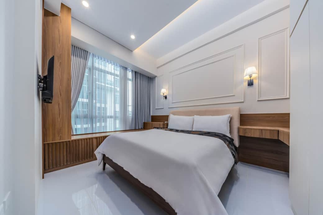 Elegant modern French-inspired bedroom with bespoke mouldings, warm wood accents, designer lighting, and a plush upholstered bed. Bright and refined, it offers a boutique-hotel feel in the heart of BGC.