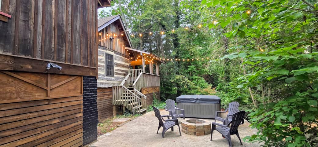 Hot tub and fire pit area sits between the cabin and the trees.
