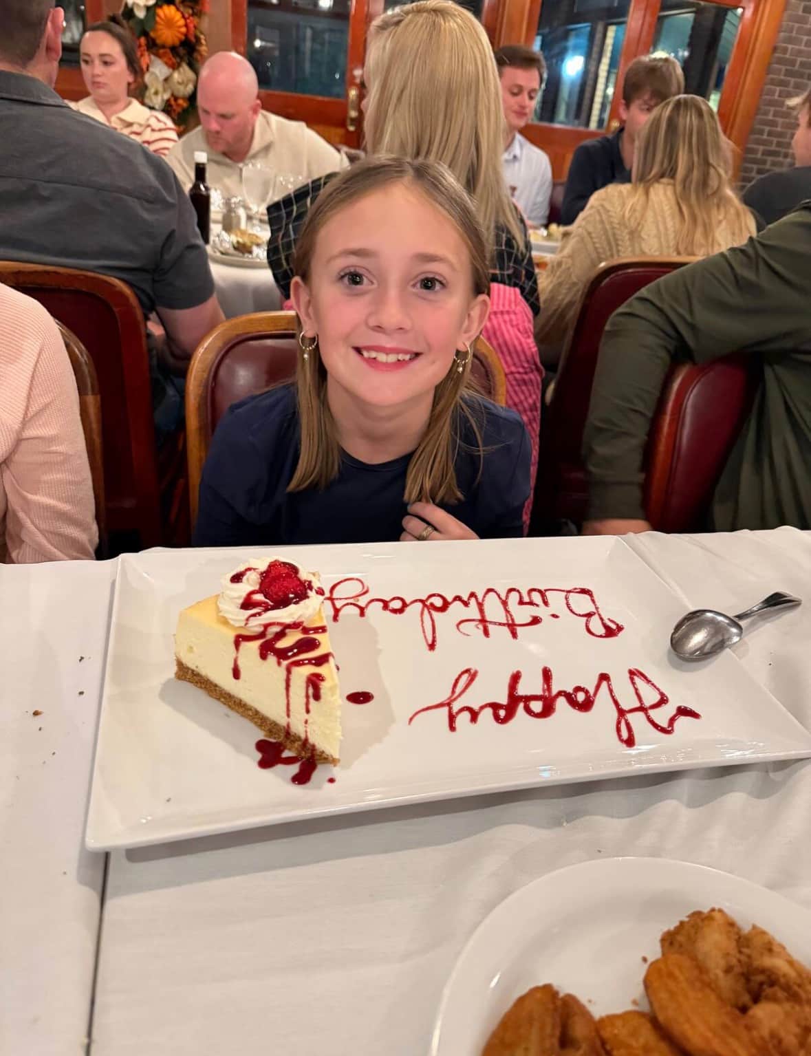 Birthday guest smiling at dinner with a birthday dessert message while cruising after departing Galveston