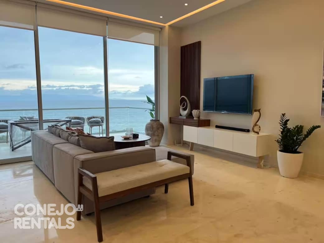 Sala con muebles acogedores y ventanales panorámicos frente al mar en Bolongo Sala con muebles acogedores y ventanales panorámicos frente al mar en Bolongo