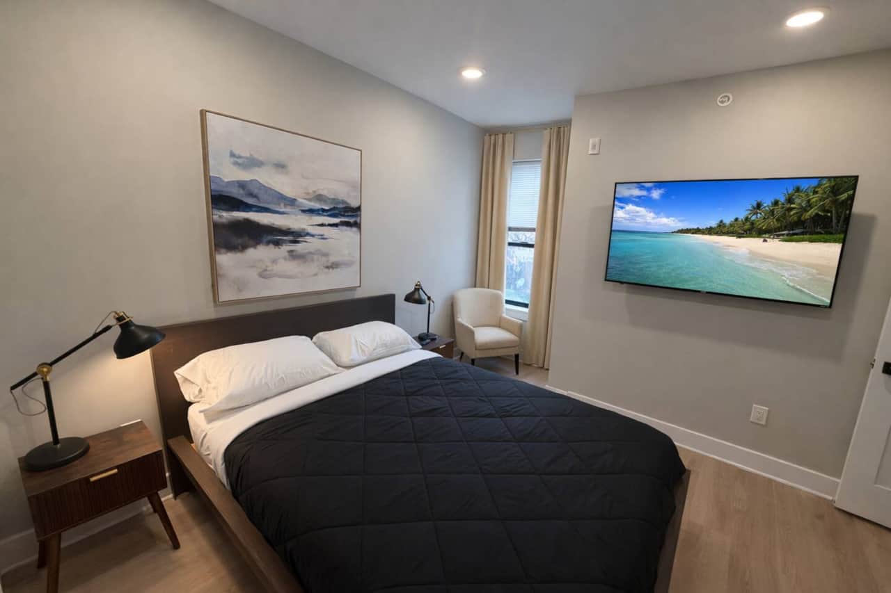 Beadeooms feature a comfortable queen-size bed with crisp white linens and a black quilted comforter. Each room includes a wall-mounted flat-screen TV, beige curtains, and a large closet.  matchingrooms are designed for a comfortable & relaxing stay!