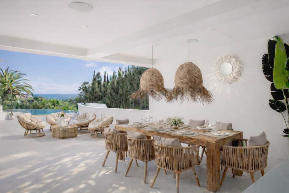 Covered outdoor dining table of Villa Luz Bliss with the pool and the sea