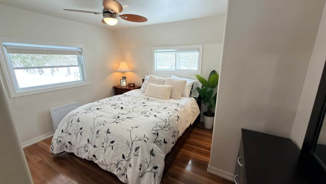 Comfortable queen bedroom with dresser, warm lighting, and convenient access to the ensuite bathroom
