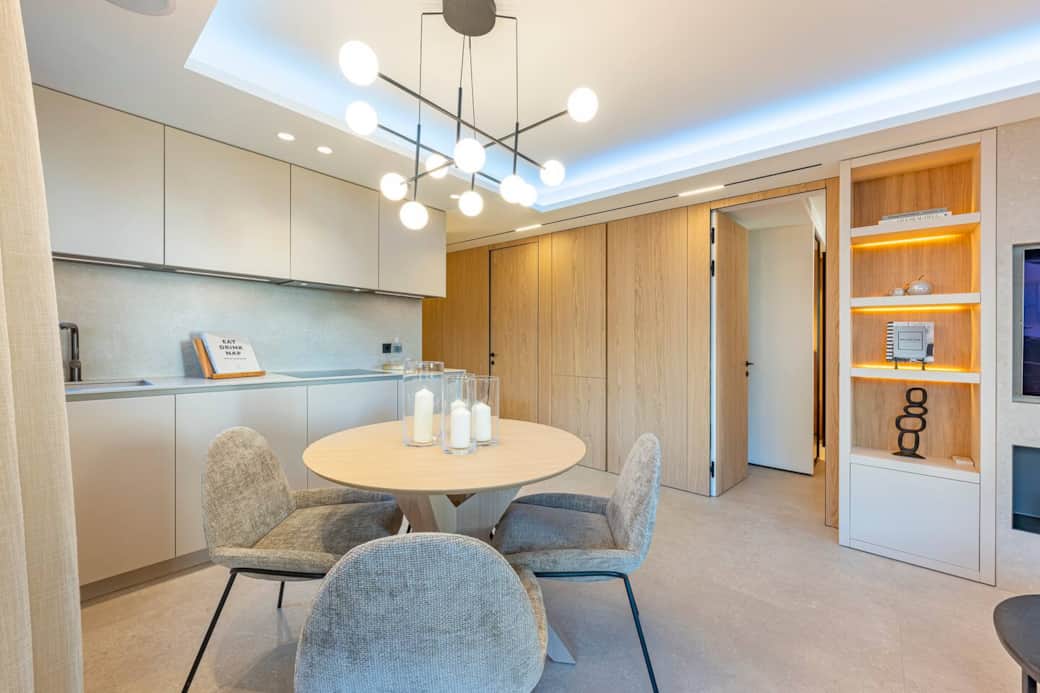 Experience the harmony of a seamless design. The kitchen, dining room, and living room are elegantly integrated behind light wood panels. A versatile, sophisticated, and serene space, where every detail is designed for your comfort and well-being.