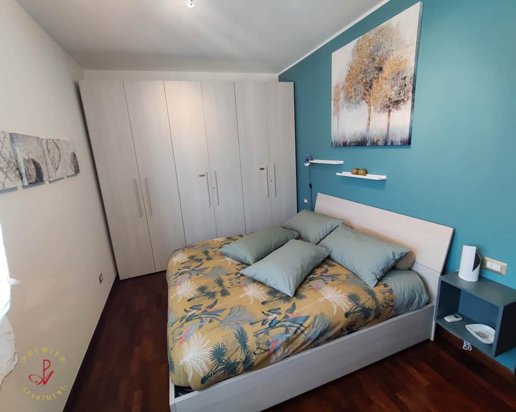 Dormitorio luminoso con suelo de parquet y armario.