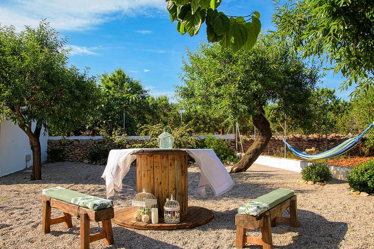 Rincón chill out en el jardín bajo la sombra de los árboles | Masía de Cholito