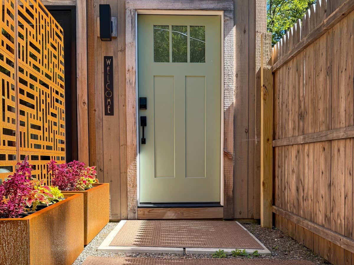 A private entrance tucked behind a tall wooden fence and a modern geometric screen.