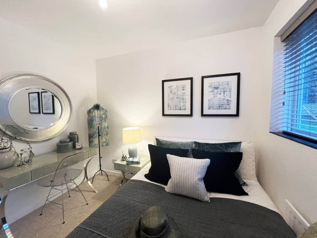The intimate 3rd bedroom features a soft colour palette of greys and whites with subtle green accents. The comfortable bed and chic decor create a calming atmosphere, ideal for restful nights. A perfect blend of style and comfort