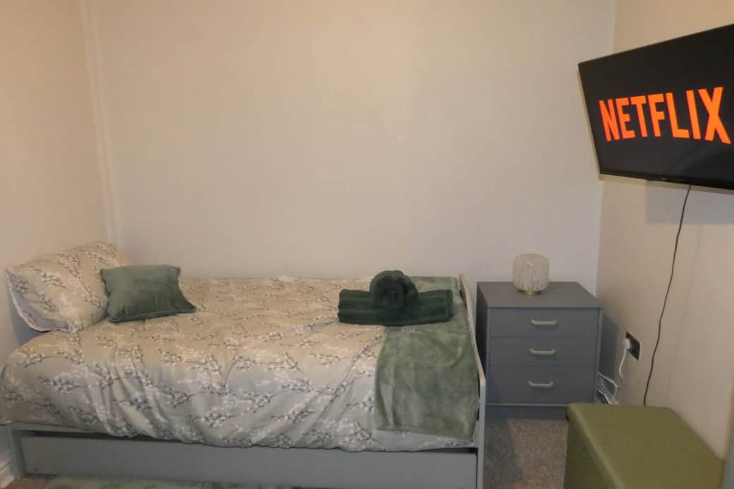 Living room with trundle bed, dining area, sofa and smart TV with wireless mobile screen sharing