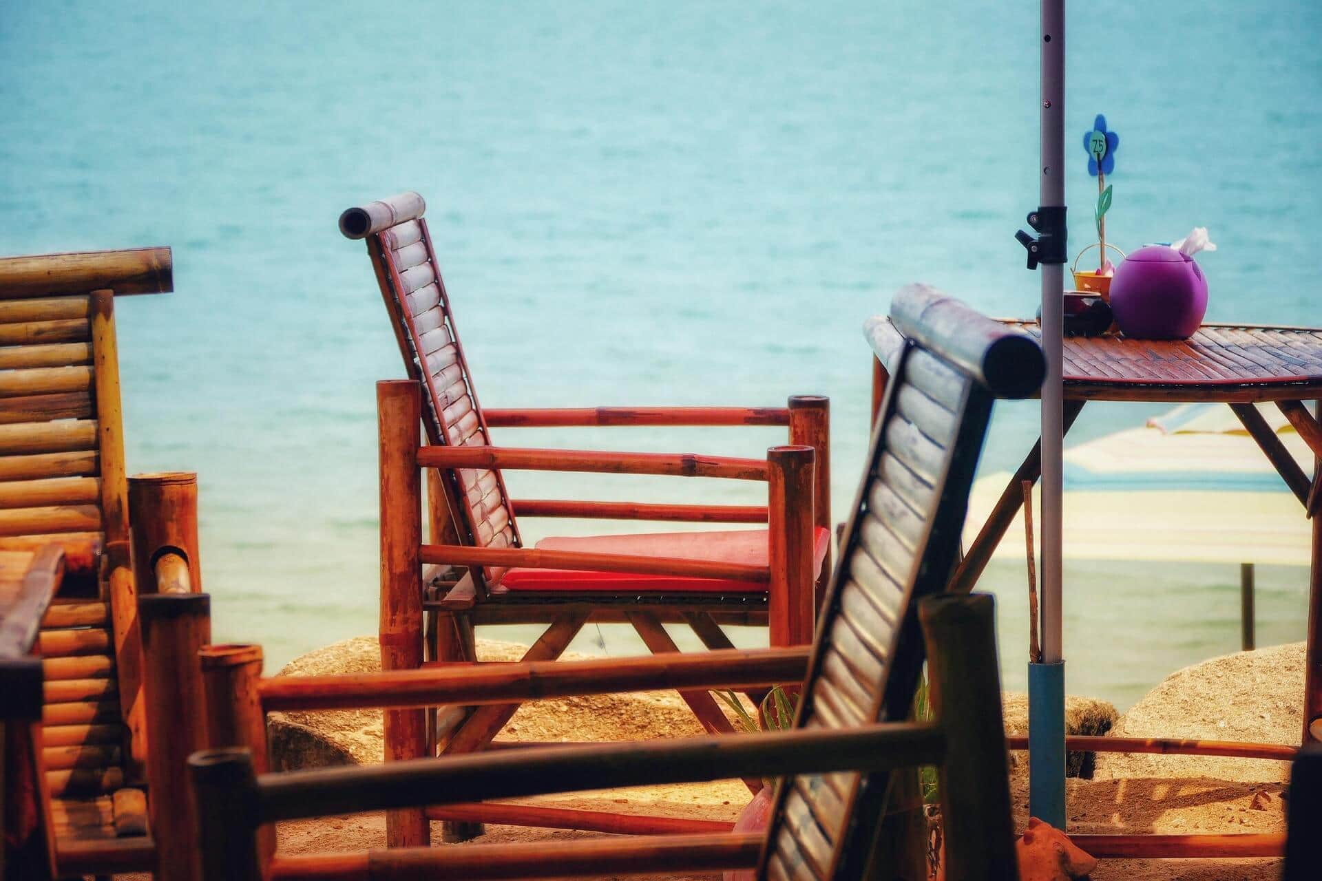 Holzstühle auf einer Terrasse mit Blick auf das Wasser, entspannte Urlaubsatmosphäre am See oder Meer.