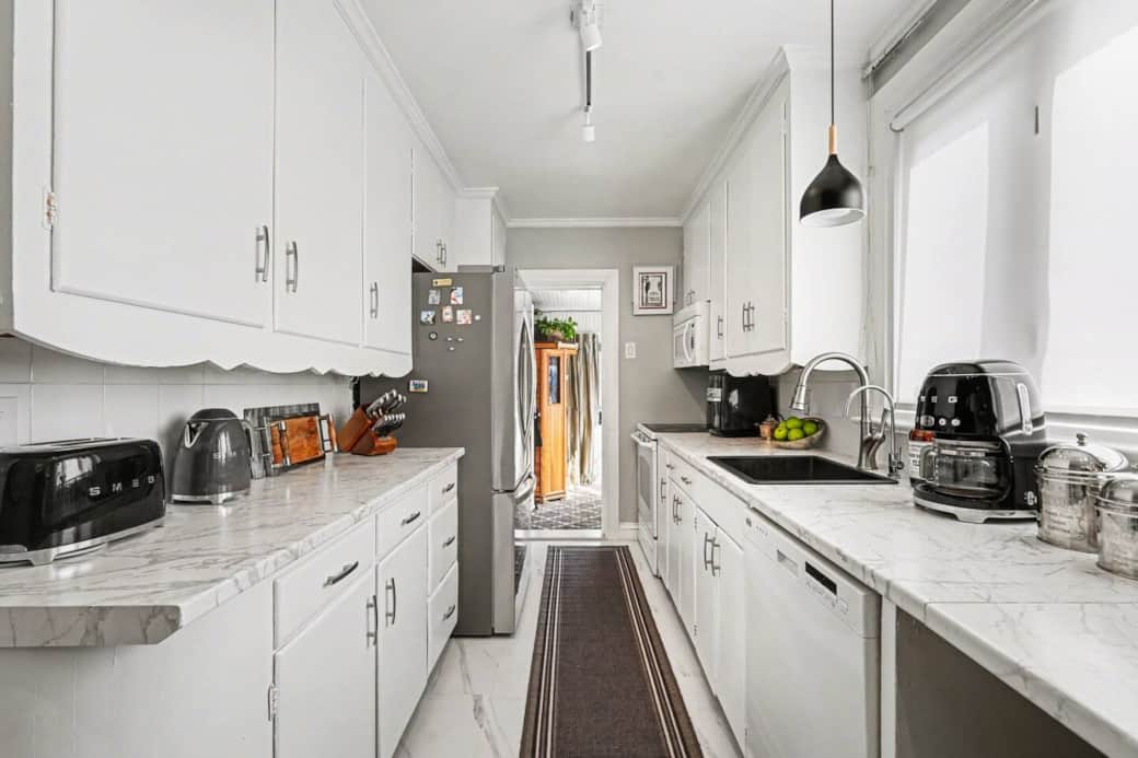 Bright galley kitchen featuring stainless steel fridge and kitchen essentials