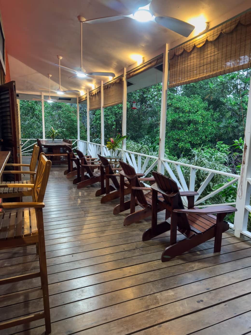 Full terrace view showcasing outdoor bar stools, Adirondack chairs, 10-seat dining table, ceiling fans, and soft lighting. A perfect gathering space for families and groups seeking relaxed island living near Bluff Beach.
