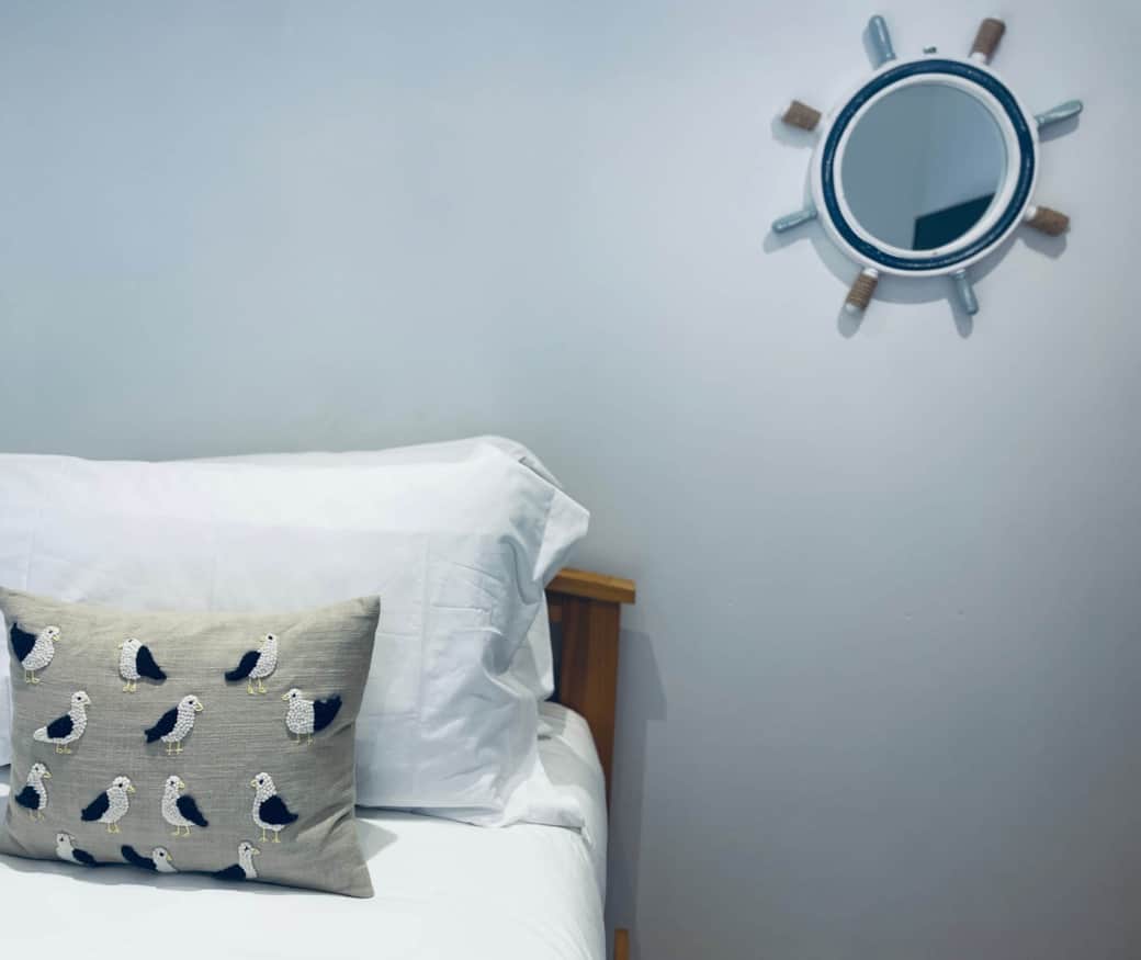 Bedroom with seagull cushion and nautical mirror at holiday rental in Ramsgate