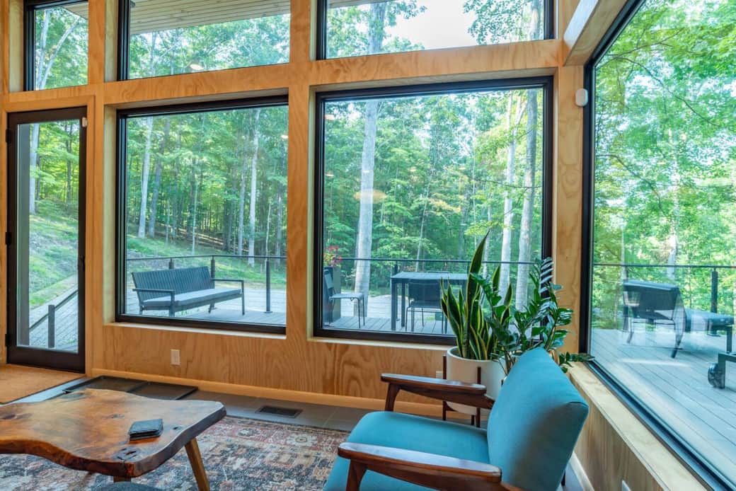 Living room with stunning wood views, sleek plywood walls, and modern furniture including a cozy blue chair—perfect for relaxing in contemporary comfort.