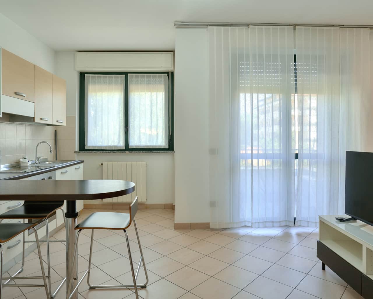 Cocina americana con mesa, sillas y ventana con cortinas ligeras