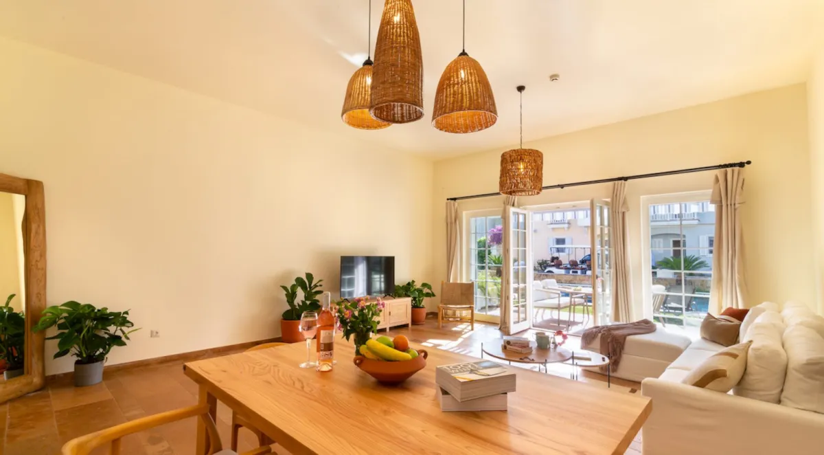 Bright living area with a dining table, sofa, and large windows overlooking the outdoor space at Portville B1 043.