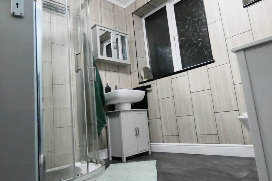 Main bathroom featuring shower cubicle with rain shower head, toilet, storage cupboards, toiletries