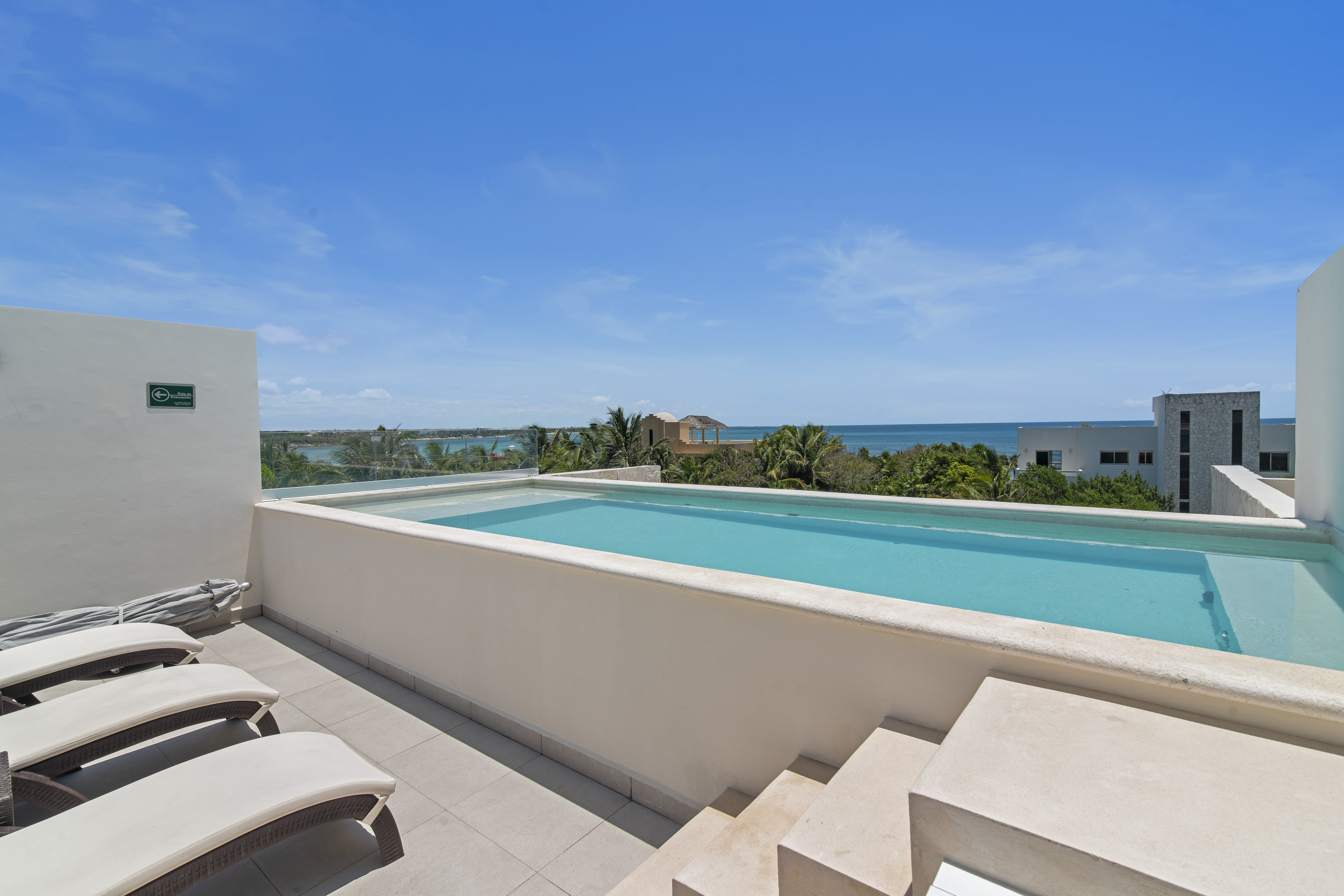 Seven rooftop pools with Caribbean Sea views, lounge chairs, umbrellas, and nearby restrooms.